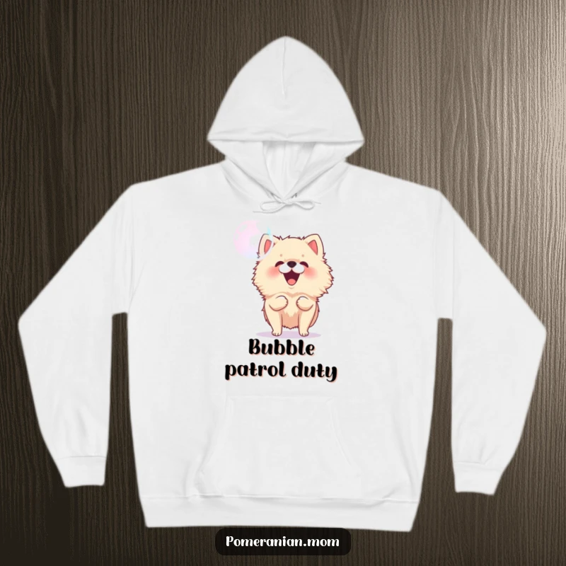 Funny Pomeranian hoodie showing a small, energetic dog happily barking at a floating bubble, radiating playful joy and warmth.