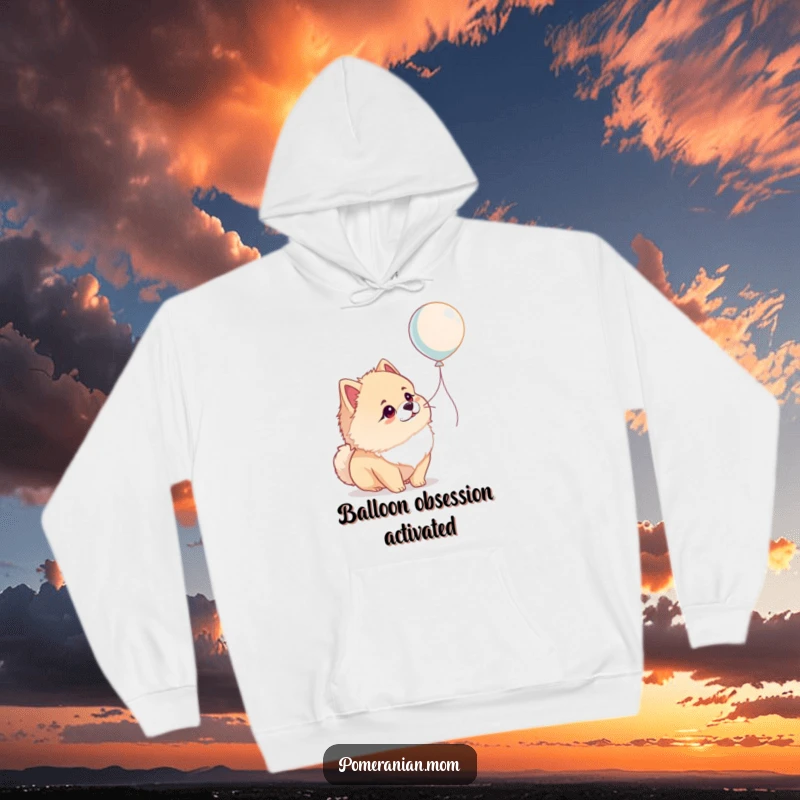 Funny Pomeranian hoodie depicting a dog in awe of a floating balloon, offering a warm, humorous, and adorable design.